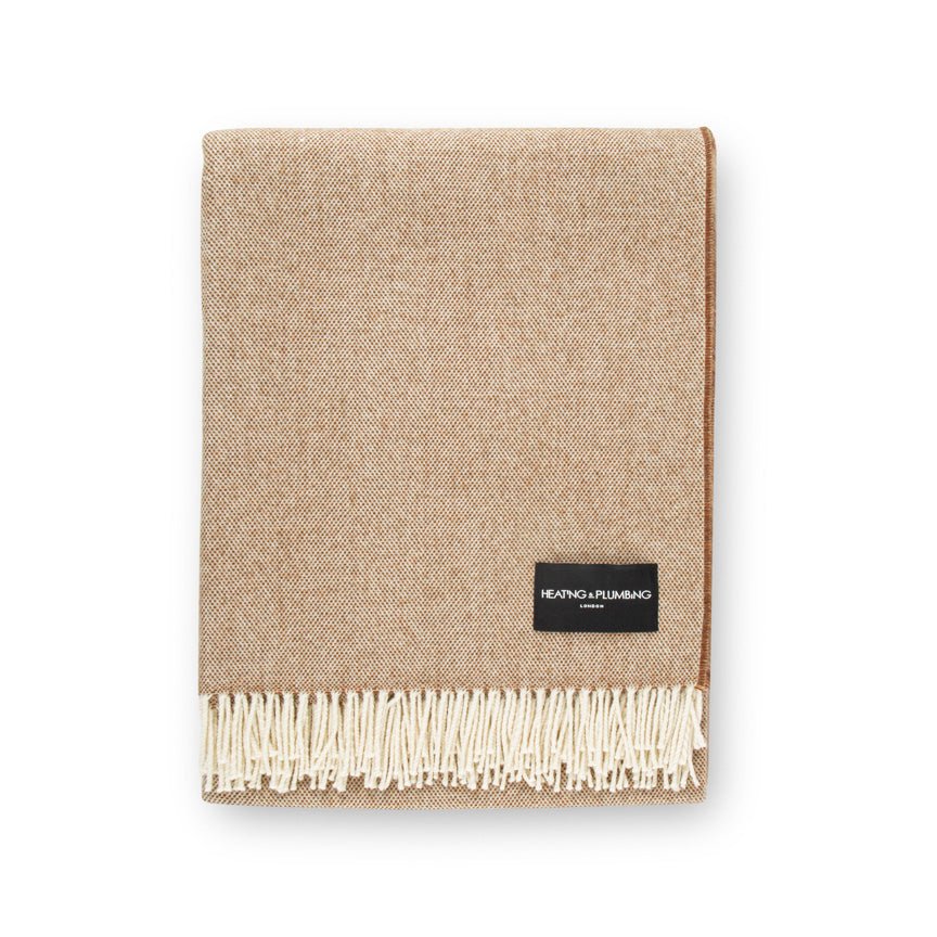 Beige woven blanket with a brand label on a white background