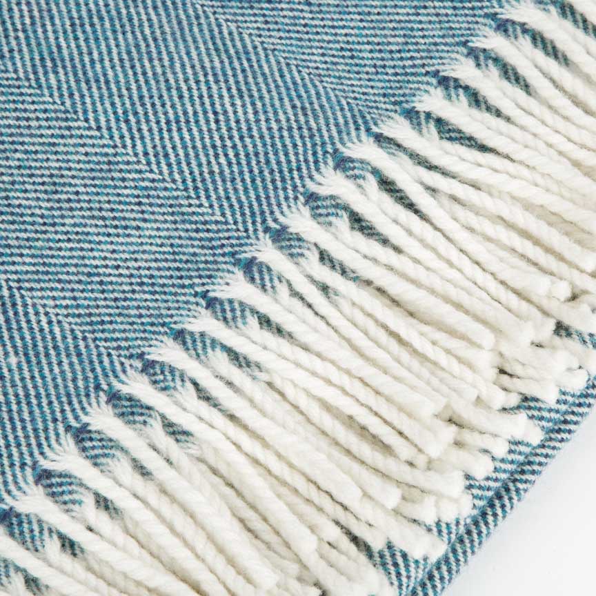 Close-up of a blue and white herringbone blanket with fringed edge