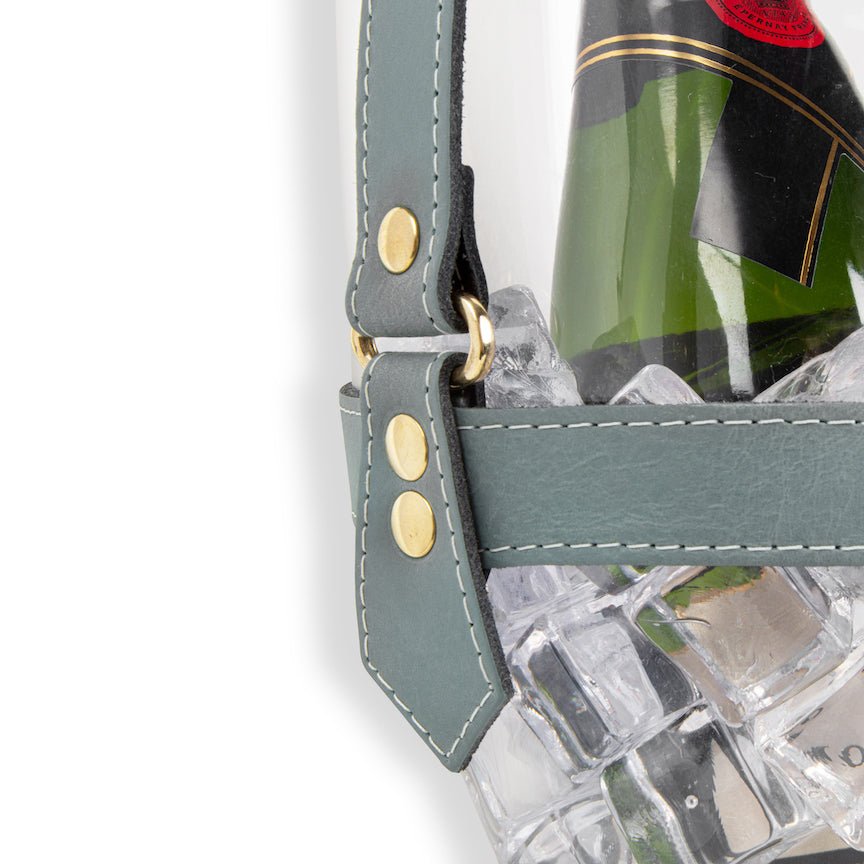 Clear champagne bucket with green bottle and ice cubes on a white background
