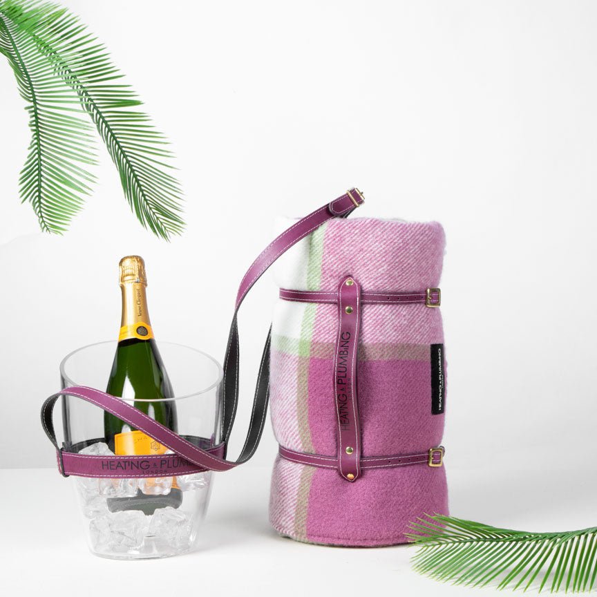 Pink plaid picnic blanket with a bottle of champagne and clear bucket on a white background