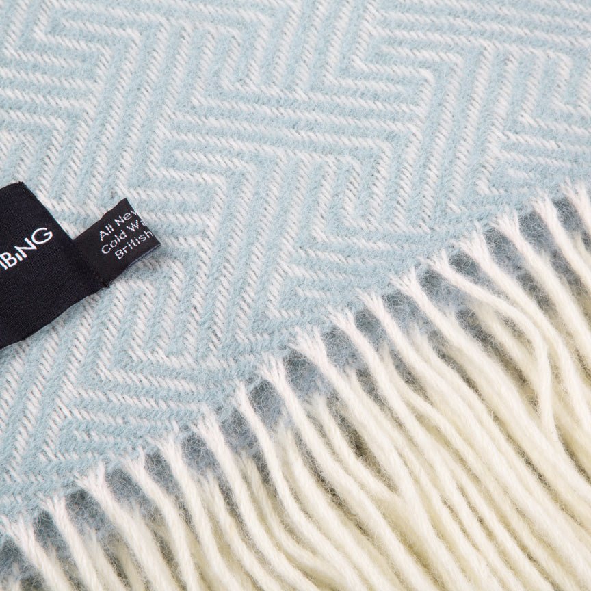 Close-up of a blue and white herringbone patterned blanket with a visible label.