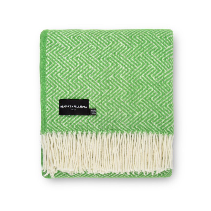 Green and white patterned throw blanket with a brand label on a white background