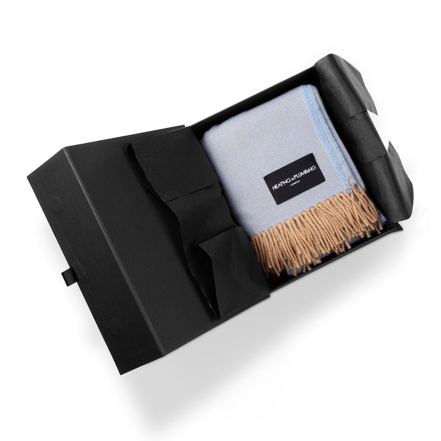 Folded blue blanket with a brand label in a black box on a white background