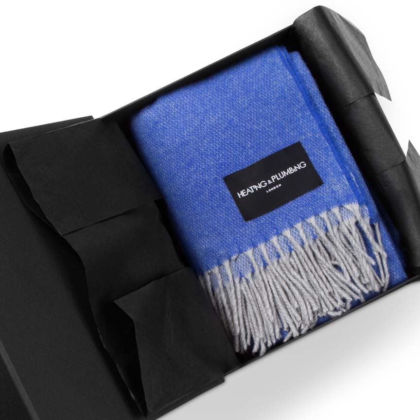 Cobalt Blue blanket with fringes in a black box, featuring a brand label Heating and Plumbing London