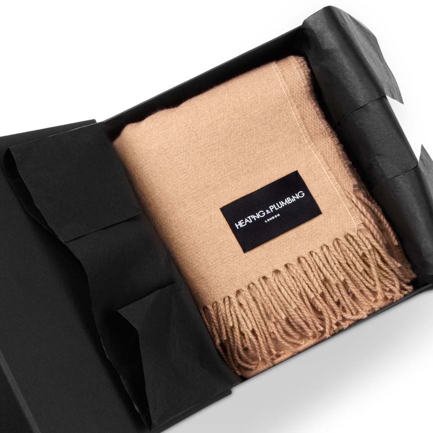 Beige blanket with a brand label in a black box on a white background