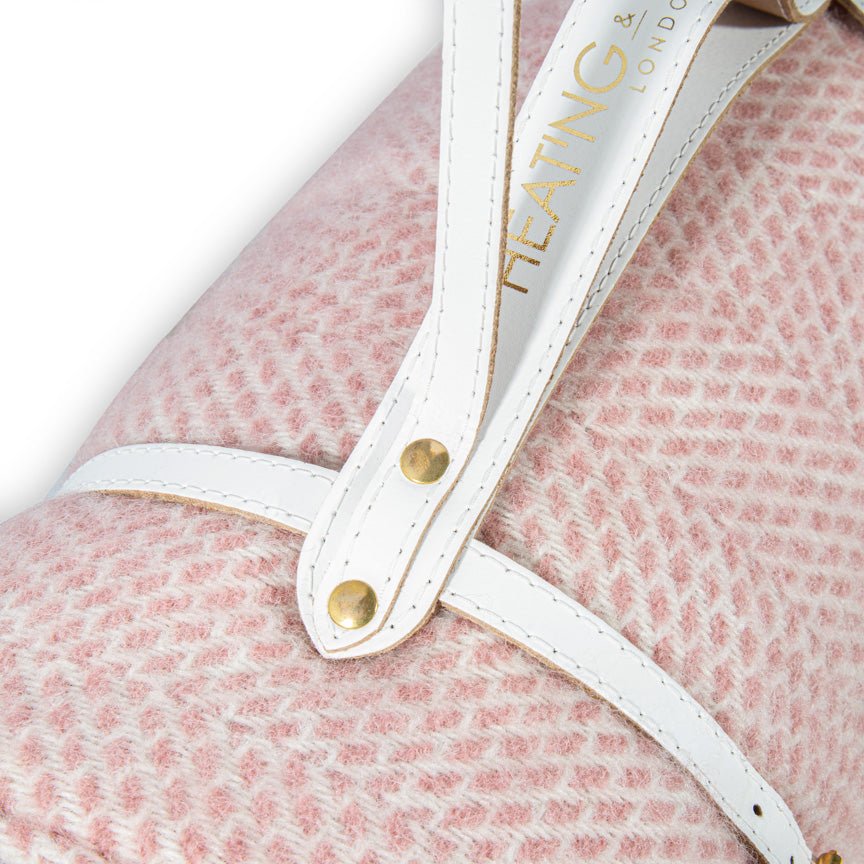 Close-up of a pink blanket with a white strap and gold accents, featuring the brand 'Heating & Plumbing London'.