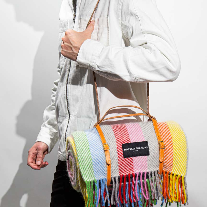 Person holding a colourful blaket with a brand label against a white background