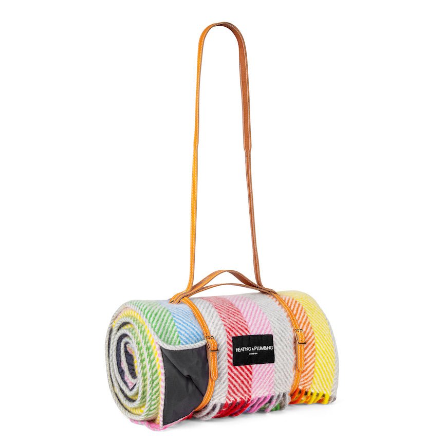 Colourful rolled-up blanket with a yellow carrying strap on a white background