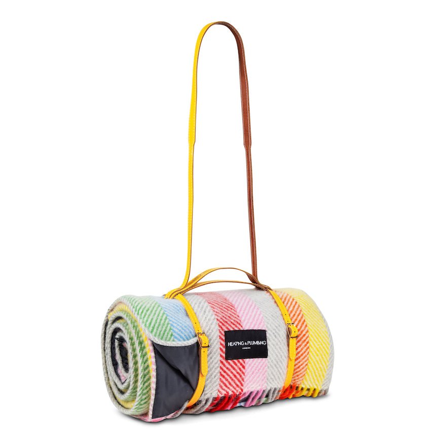 Colourful rolled-up blanket with a carrying strap on a white background