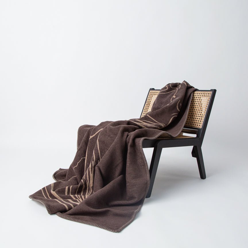 Brown blanket draped over a black chair with a white background