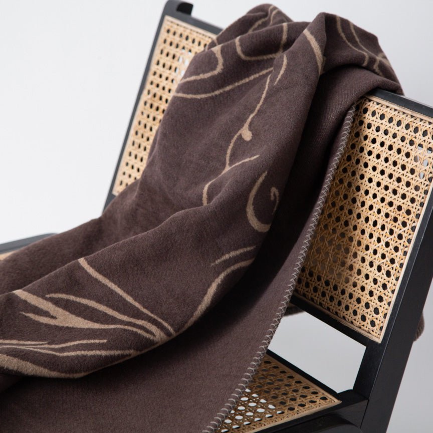 Brown patterned blanket draped over a chair with perforated design