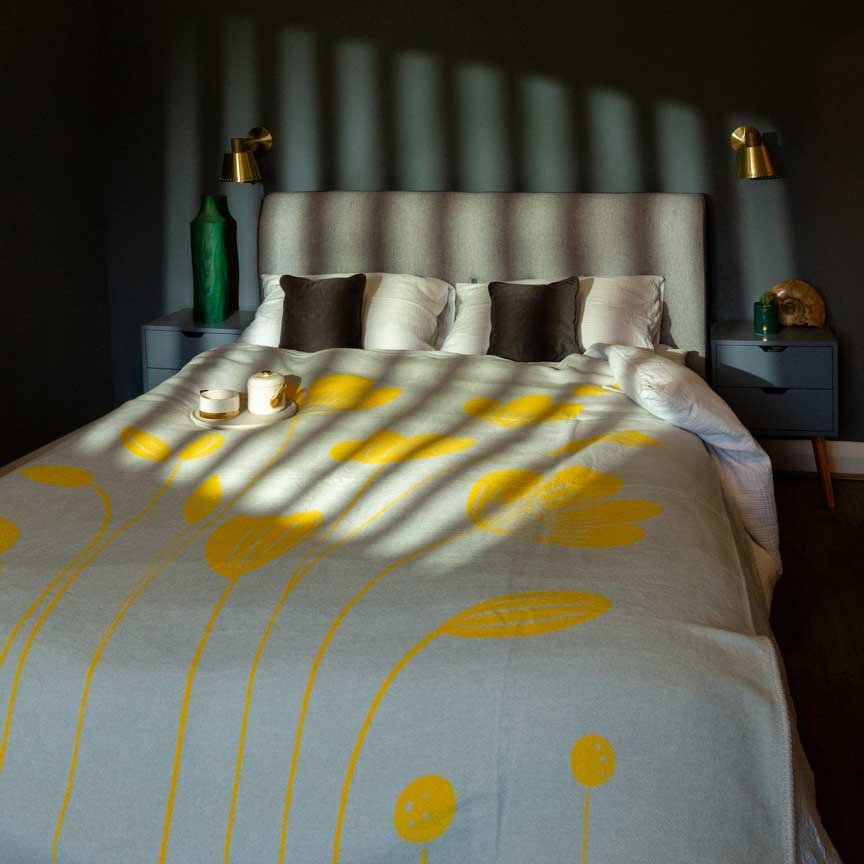 Bed with yellow and white patterned bedding in a dimly lit room.