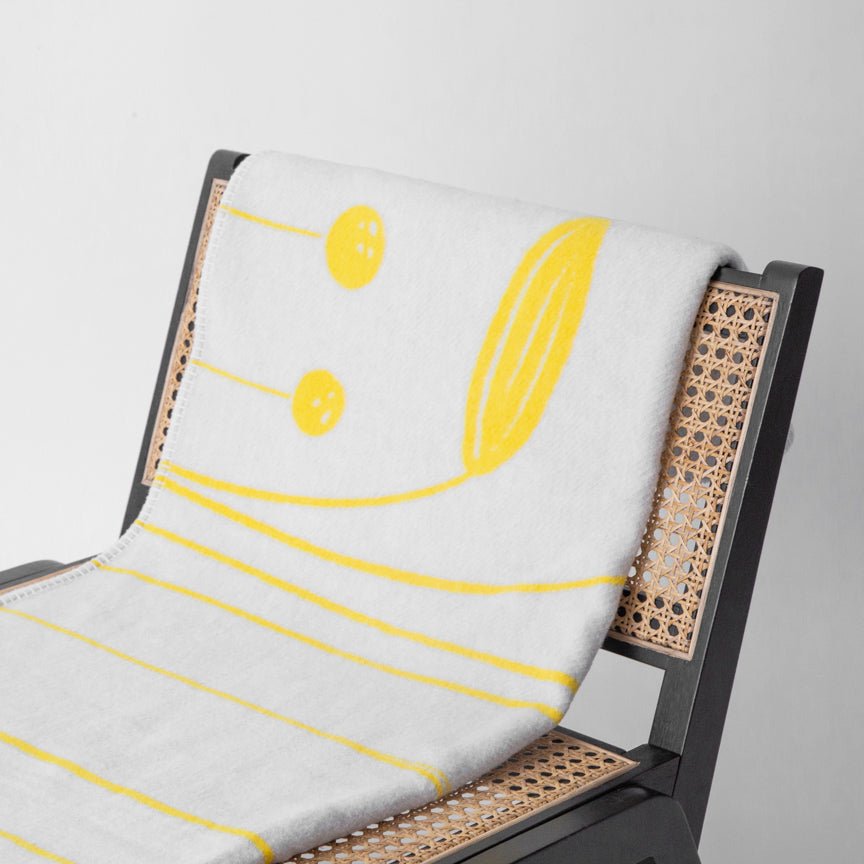Chair with a white blanket featuring yellow abstract design on a grey background
