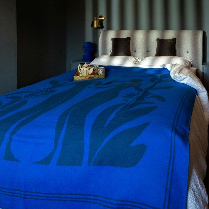 Bed with blue floral-patterned blanket in a bedroom setting