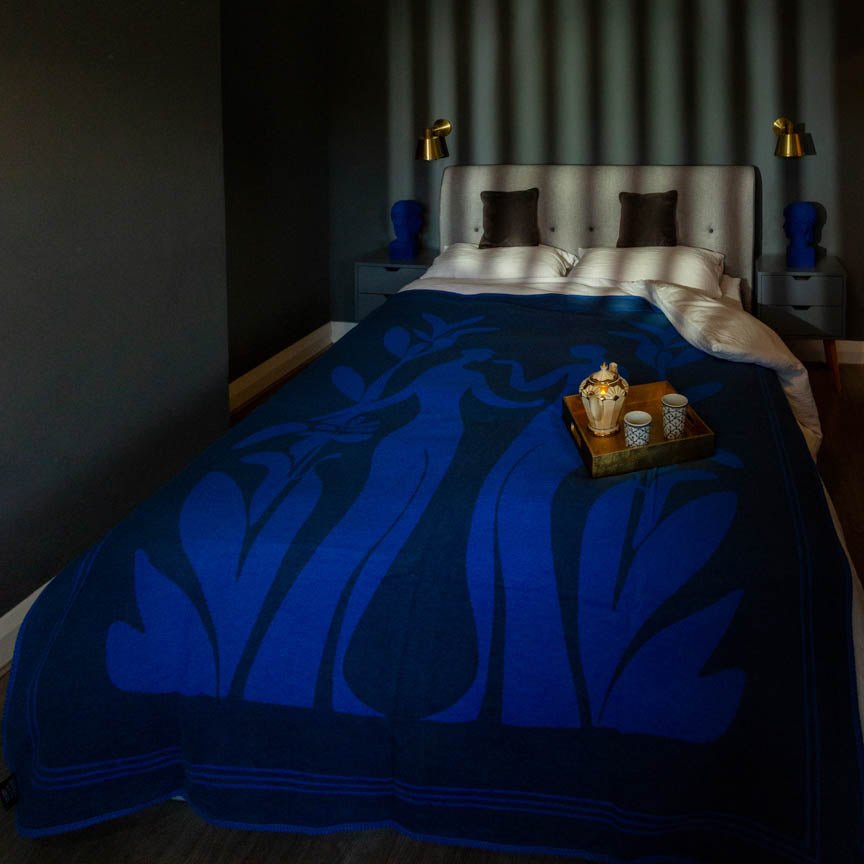 Bed with blue blanket and tray of items in a dimly lit room