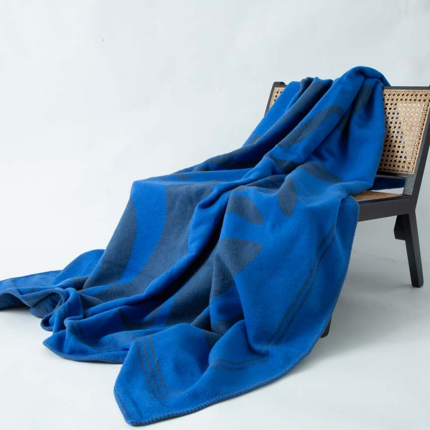 Blue blanket draped over a chair on a light grey background