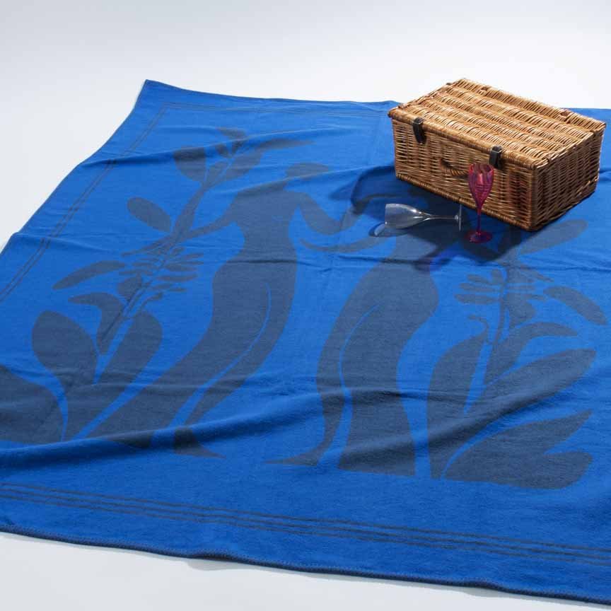 Blue blanket with leaf patterns and a wicker picnic basket on a white background