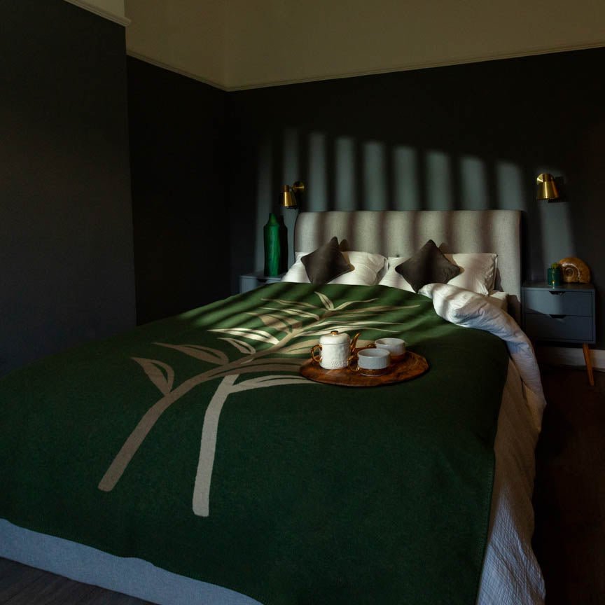 Bed with green blanket and decorative items in a dimly lit room