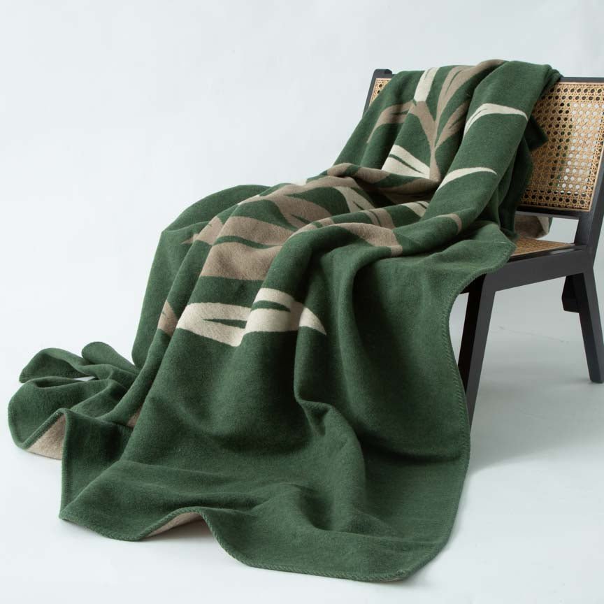 Green patterned blanket draped over a chair on a white background