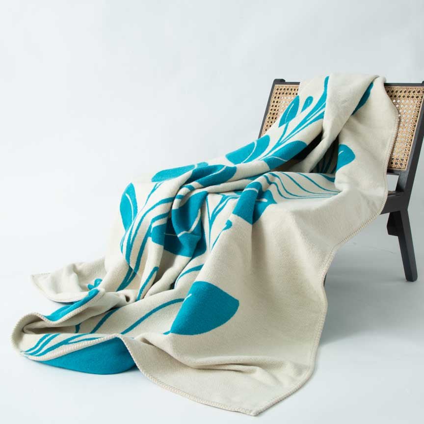 Beige and blue patterned blanket draped over a chair on a light grey background