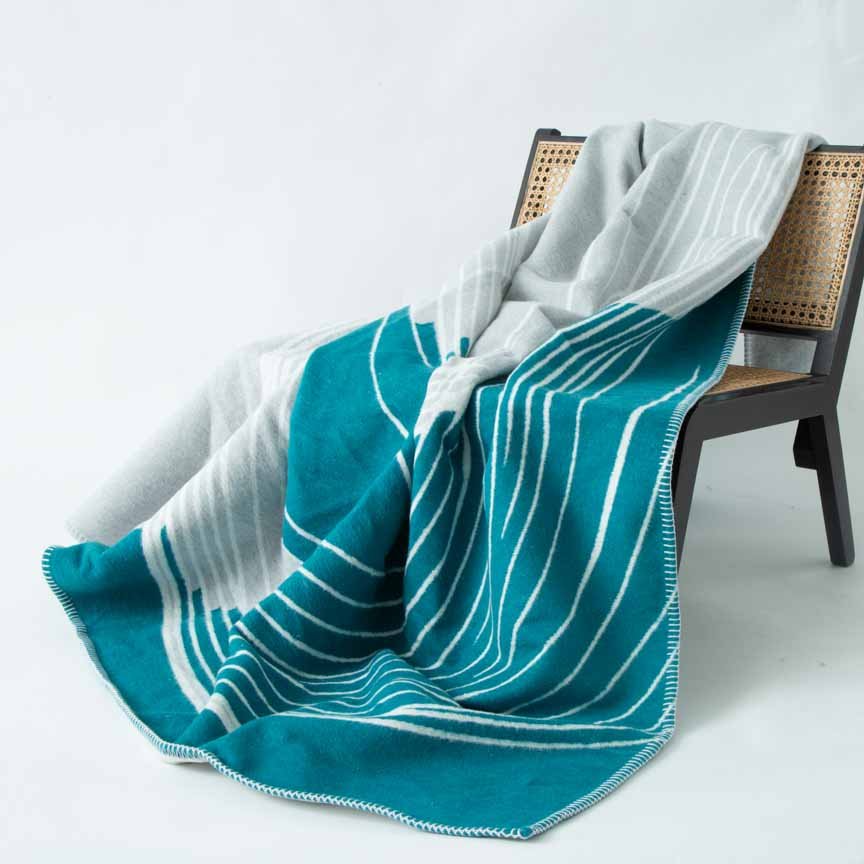 Teal and white striped blanket draped over a chair on a light grey background