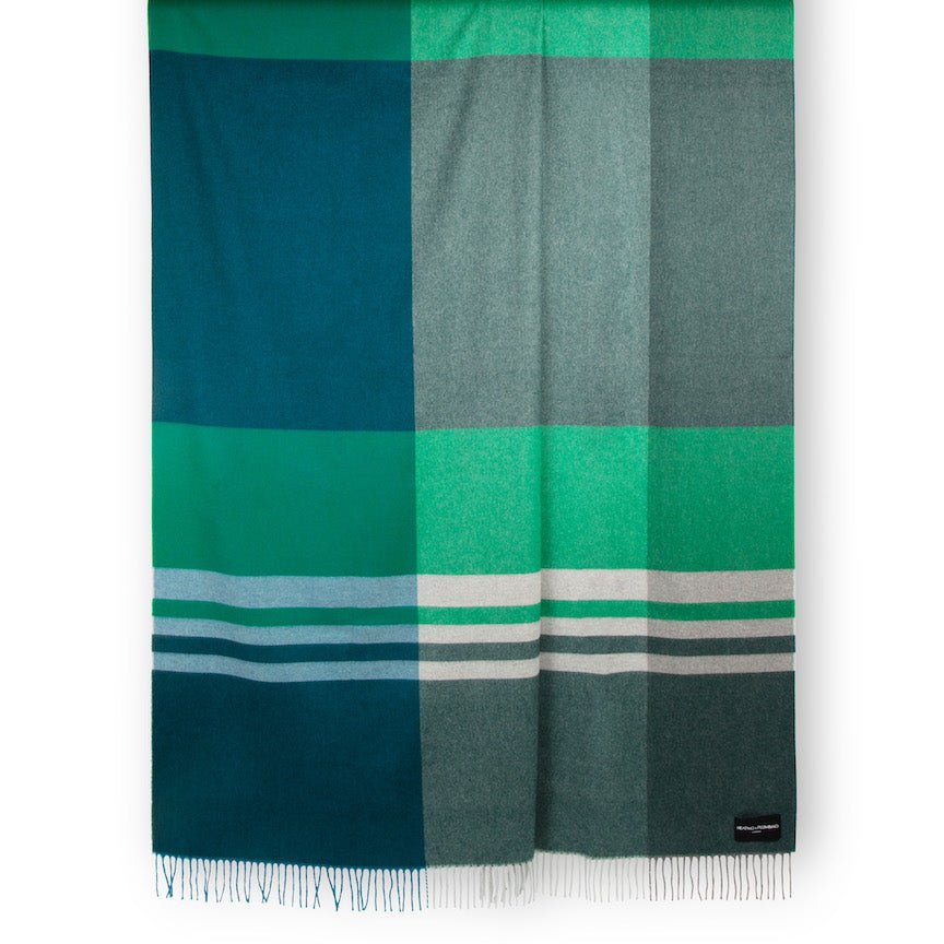 Green and blue plaid blanket with a brand label on a white background