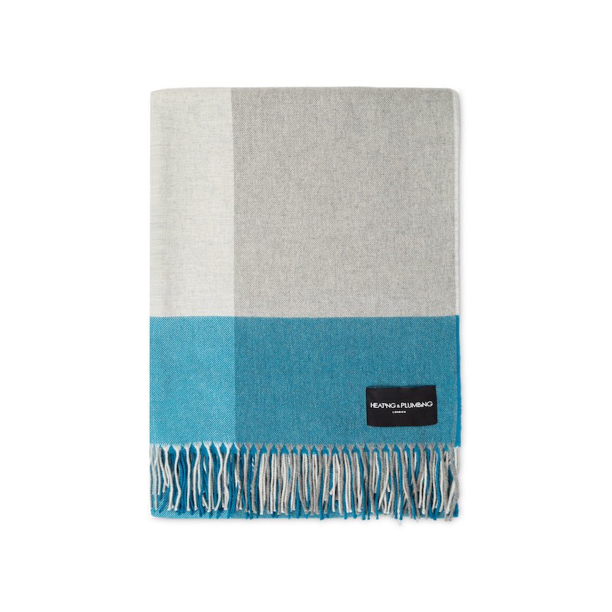 Grey and blue plaid blanket with a brand label on a white background