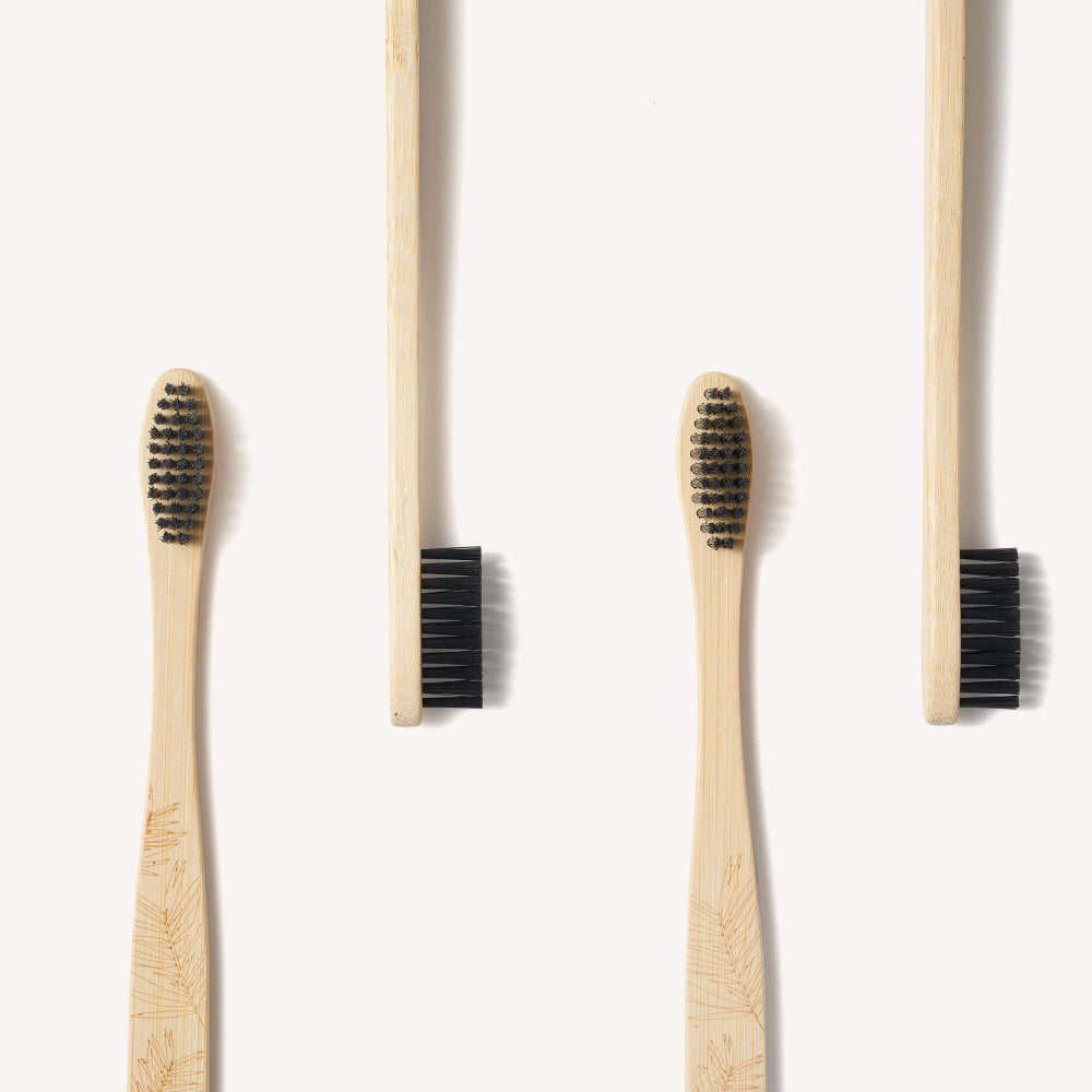 Four bamboo toothbrushes close up of black bristles on a white background