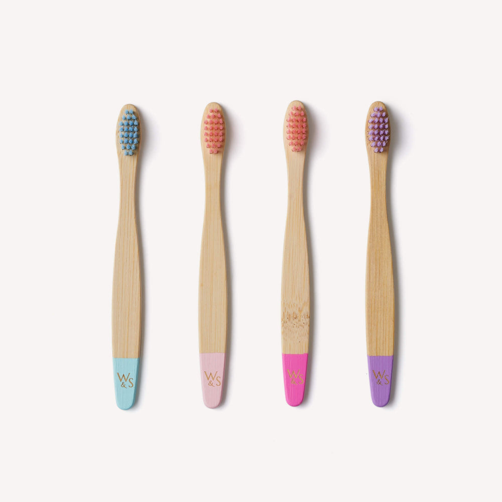 Four bamboo toothbrushes with coloured handles on a white background