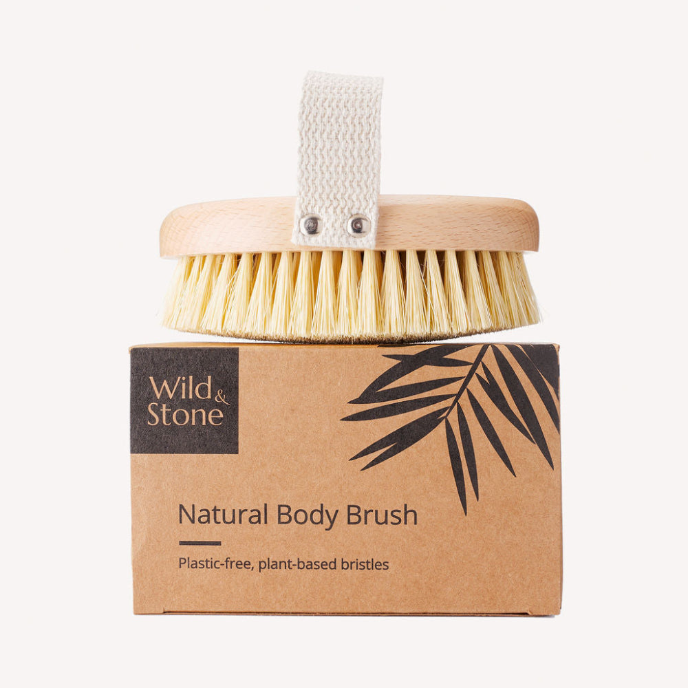 Natural body brush with handle and plant-based bristles on a cardboard packaging labelled 'Wild & Stone'.