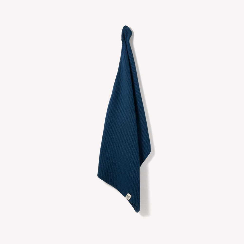 Ocean blue organic hand towel hanging on a white background