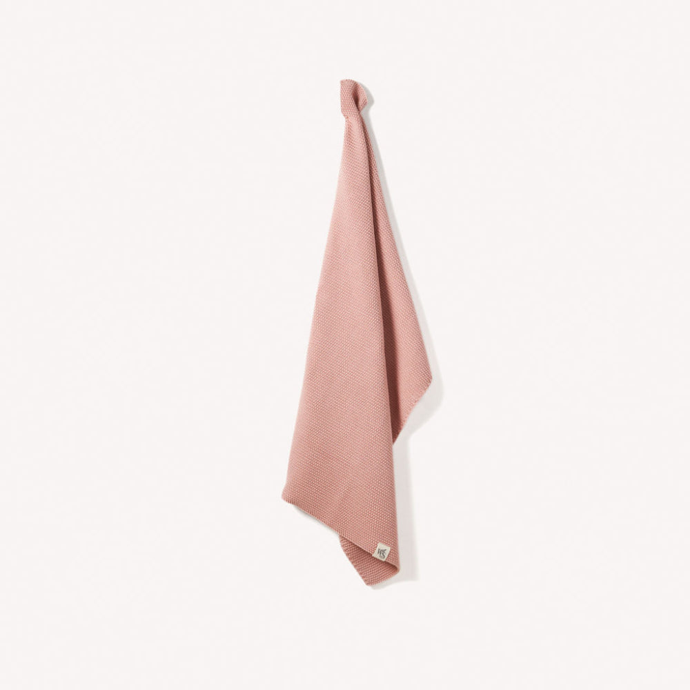 Pink organic textured hand towel hanging on a white background