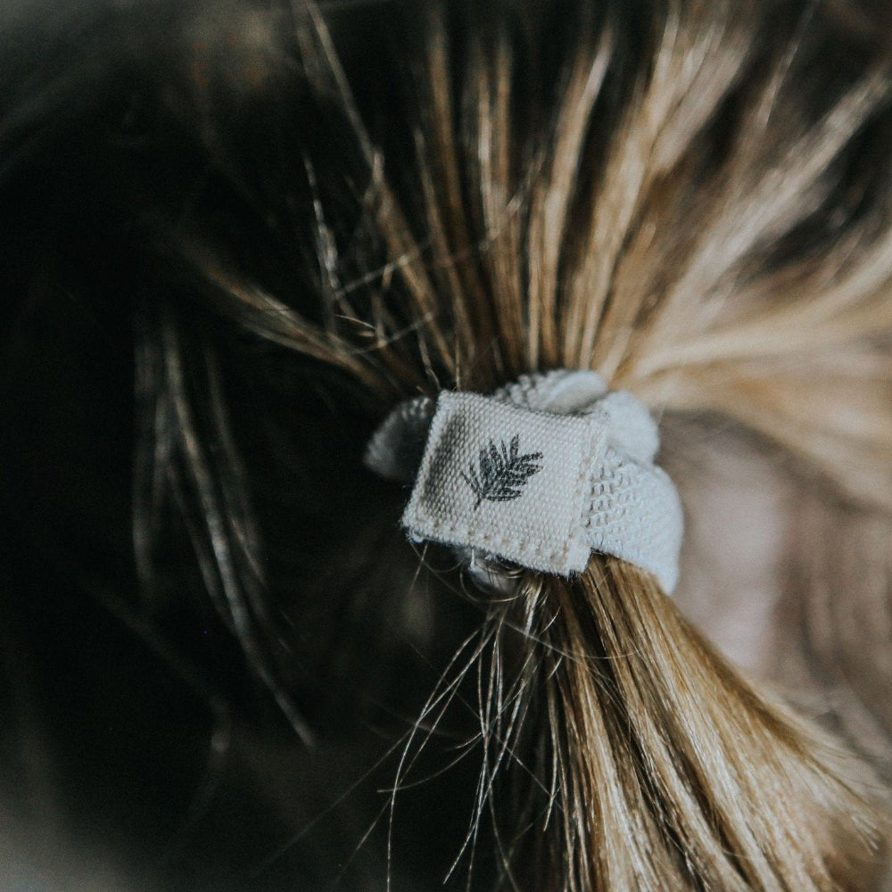 Close-up of a hair tie with a leaf design in a ponytail.
