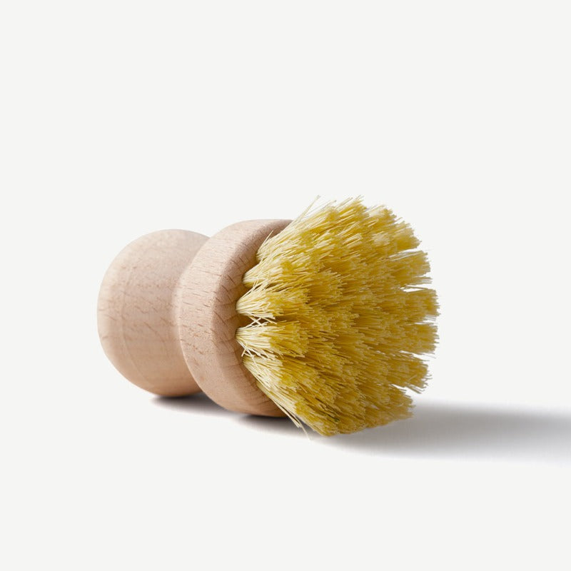 Wooden dish brush with yellow bristles on a white background