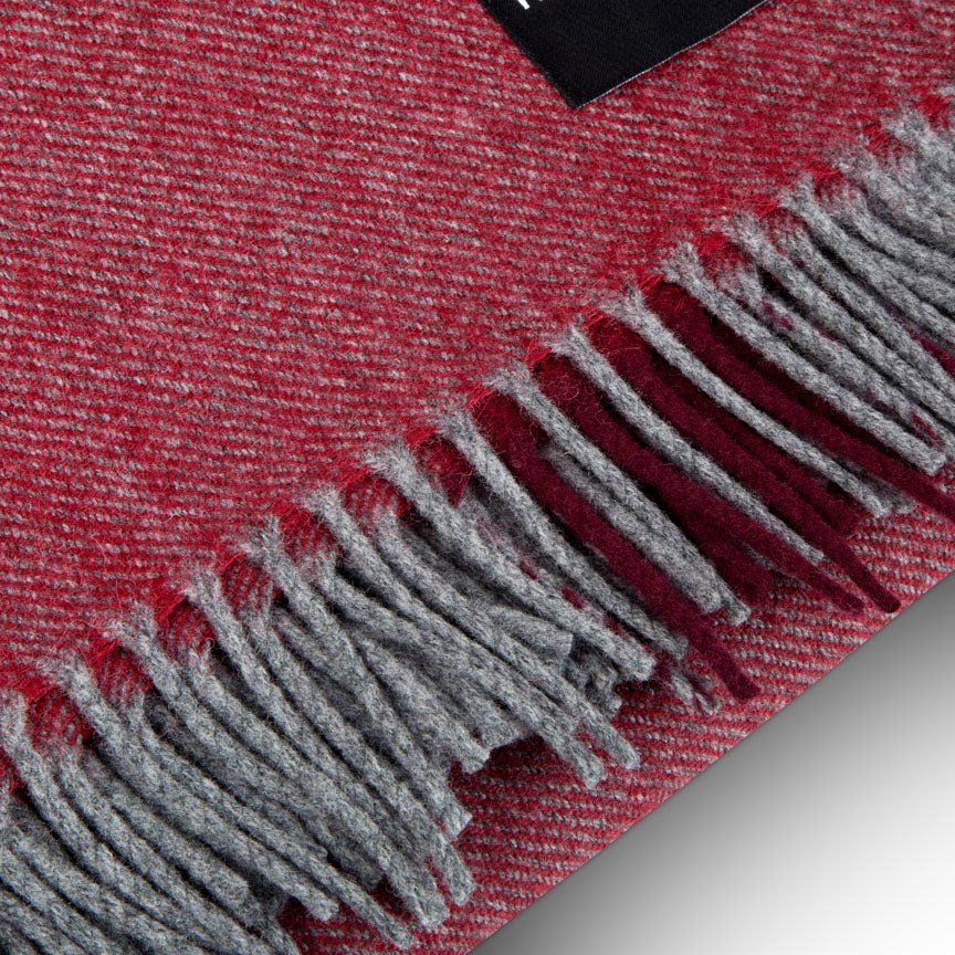 Close-up of a red and grey checkered blanket with fringes on a light gray background