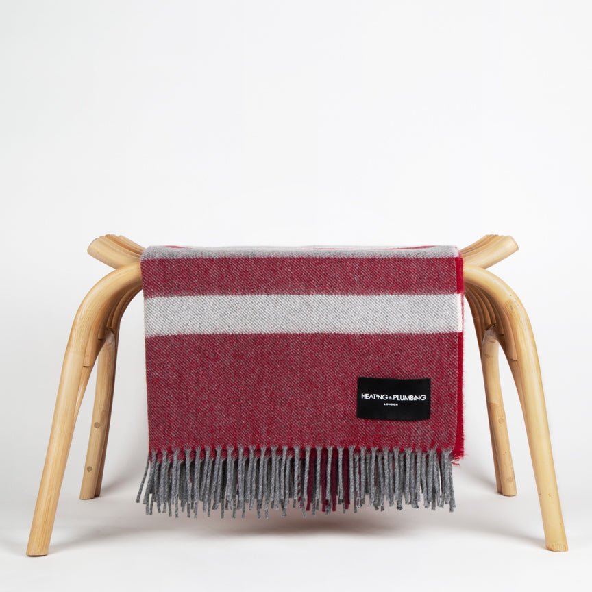 Red and grey striped blanket draped over a wooden chair on a white background