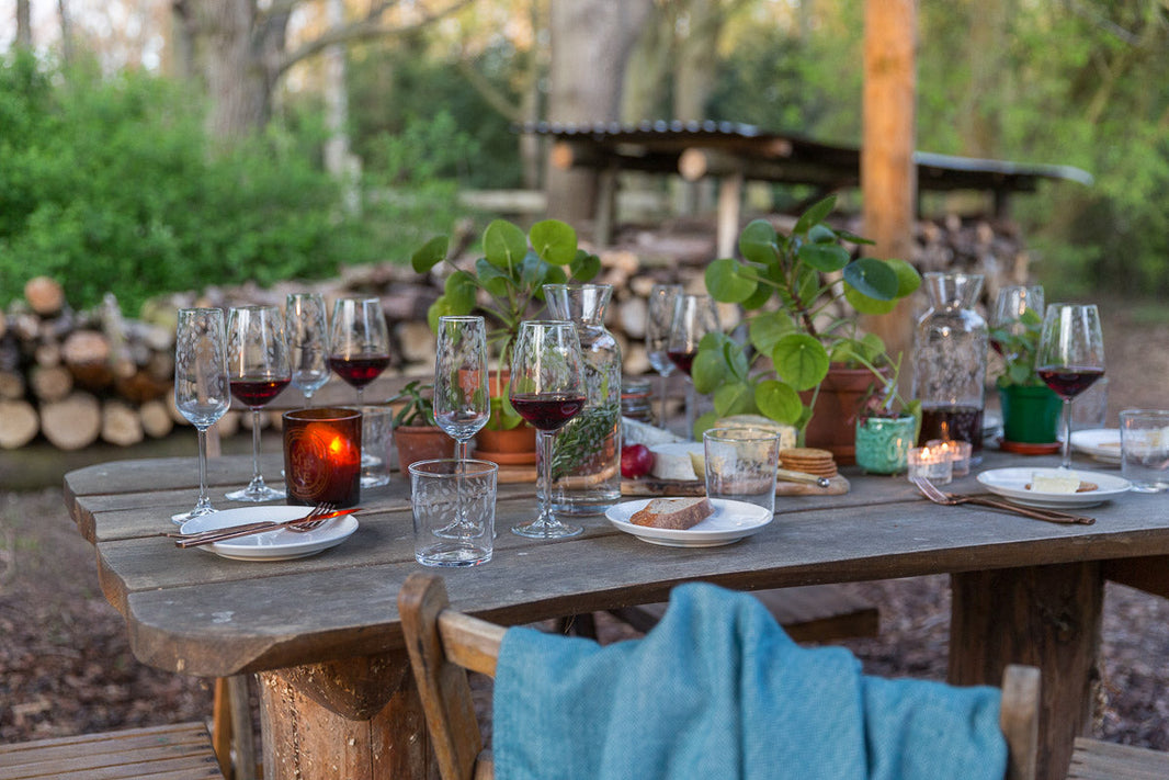 Outdoor Dinner table with wine glasses and plates set with a blanket