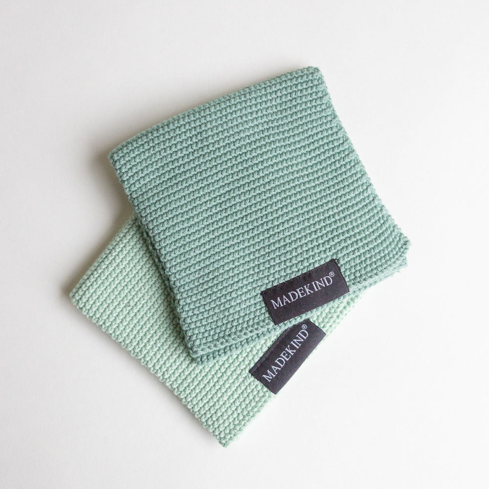 Two light green dishcloths with 'MADEKIND' labels on a white background