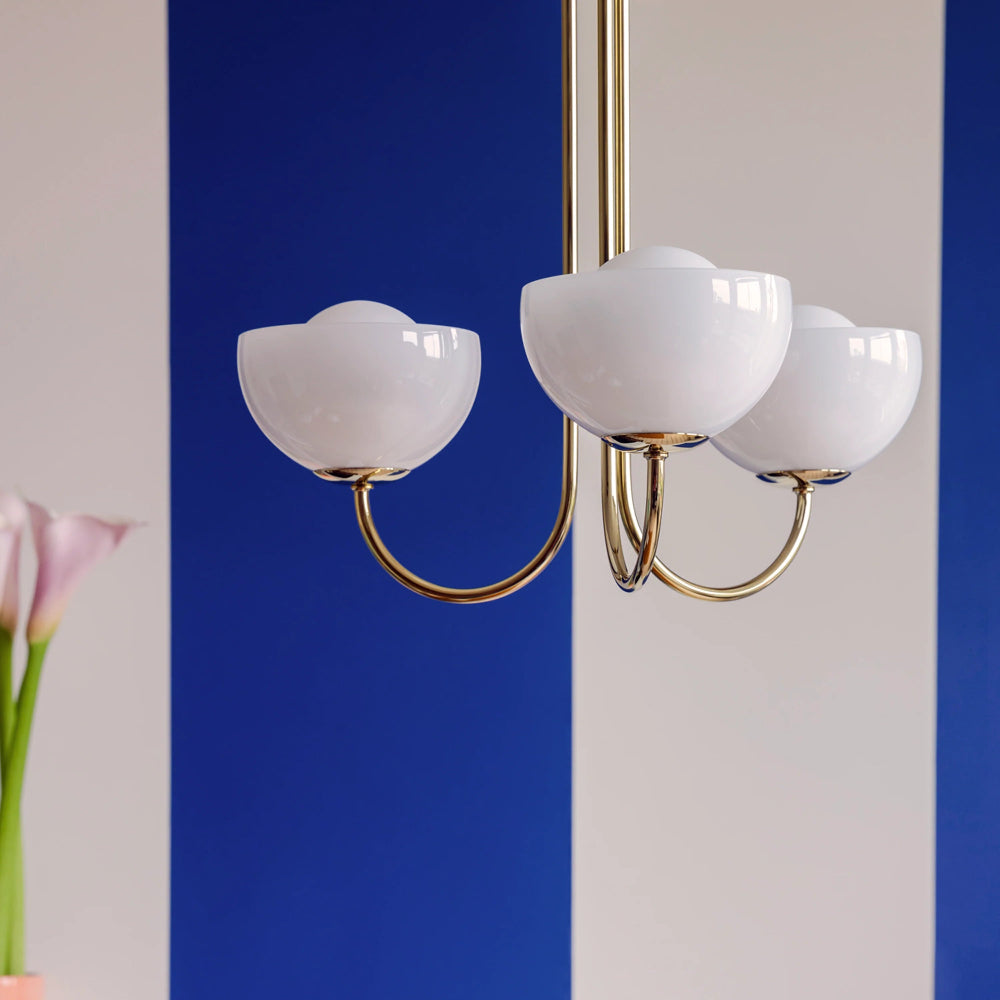 Chandelier with white glass shades and gold metal arms against a blue and gray background