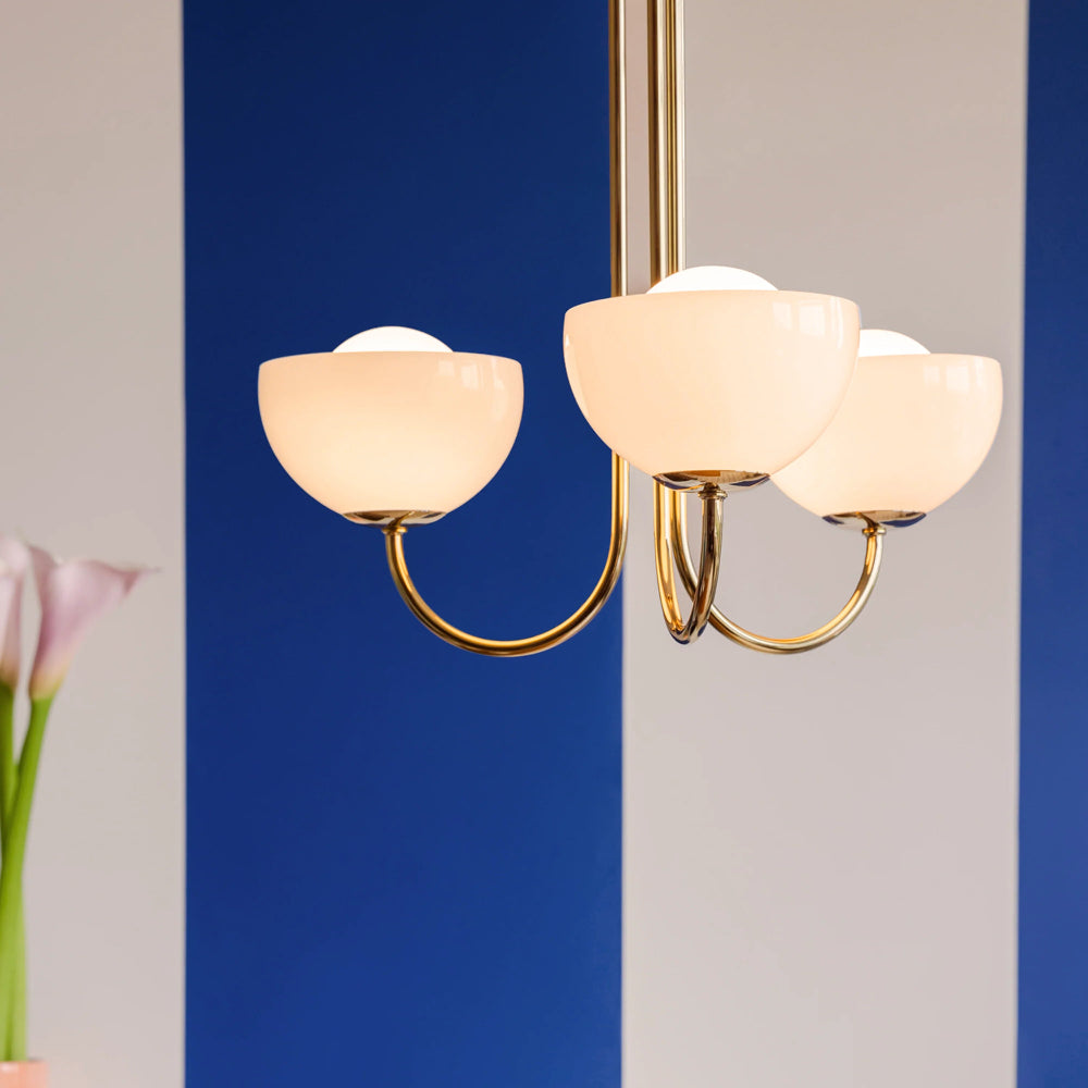 Three-light ceiling with gold frame and white glass shades against a blue and gray background.
