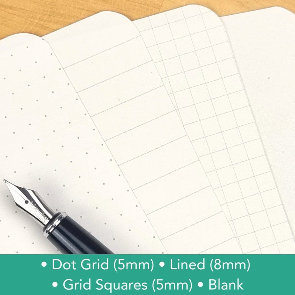 Sheet of grid paper with a pen on a wooden surface, featuring different grid patterns.