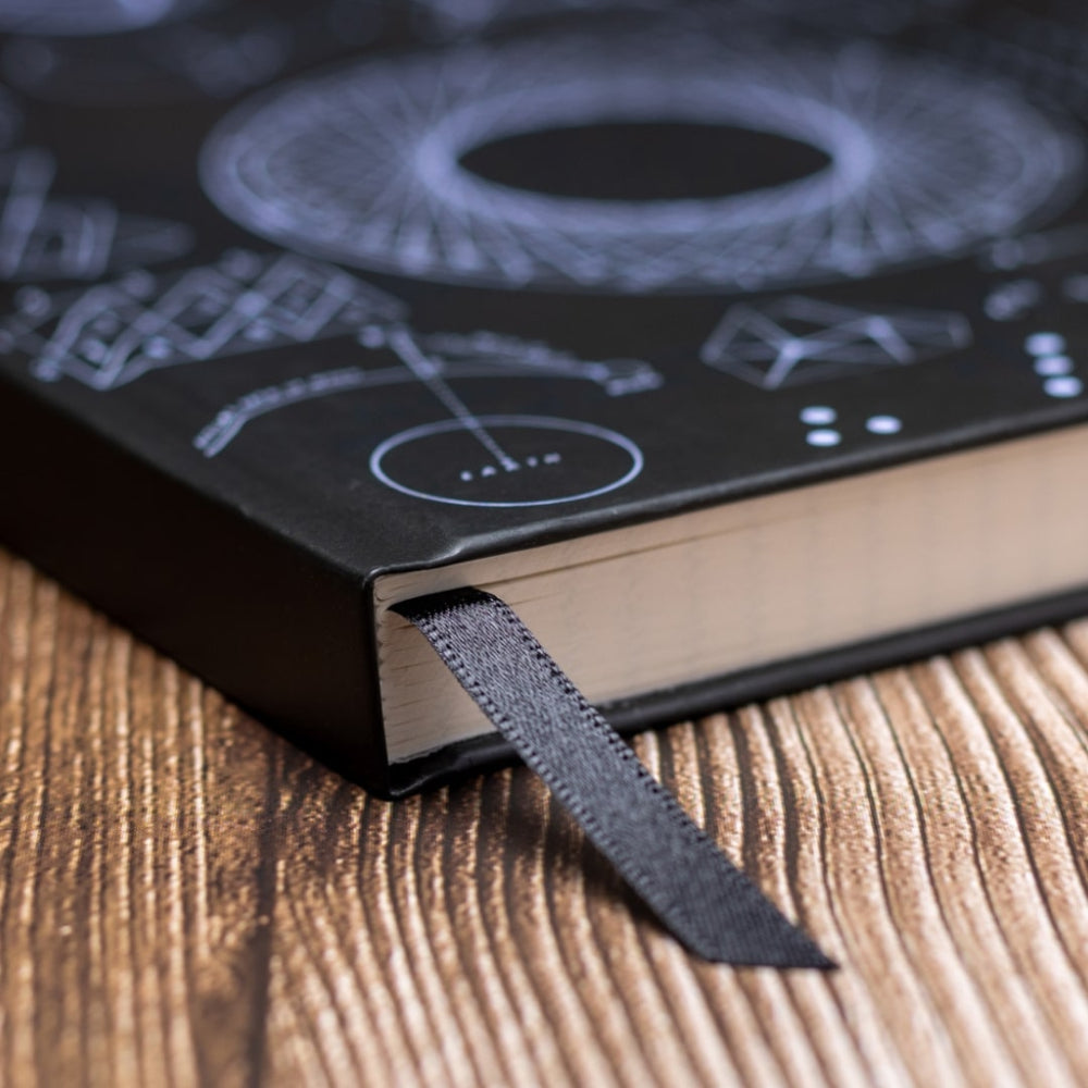 A5 Maths noteBook with a black cover featuring white designs on a wooden surface closeup bookmark ribbon
