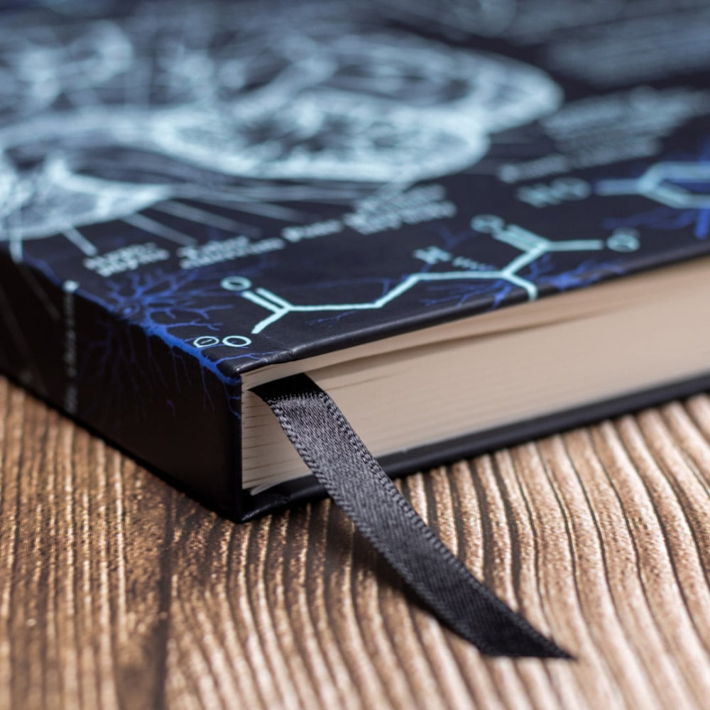A5 Neuroscience notebook with a dark blue cover featuring white designs on a wooden surface