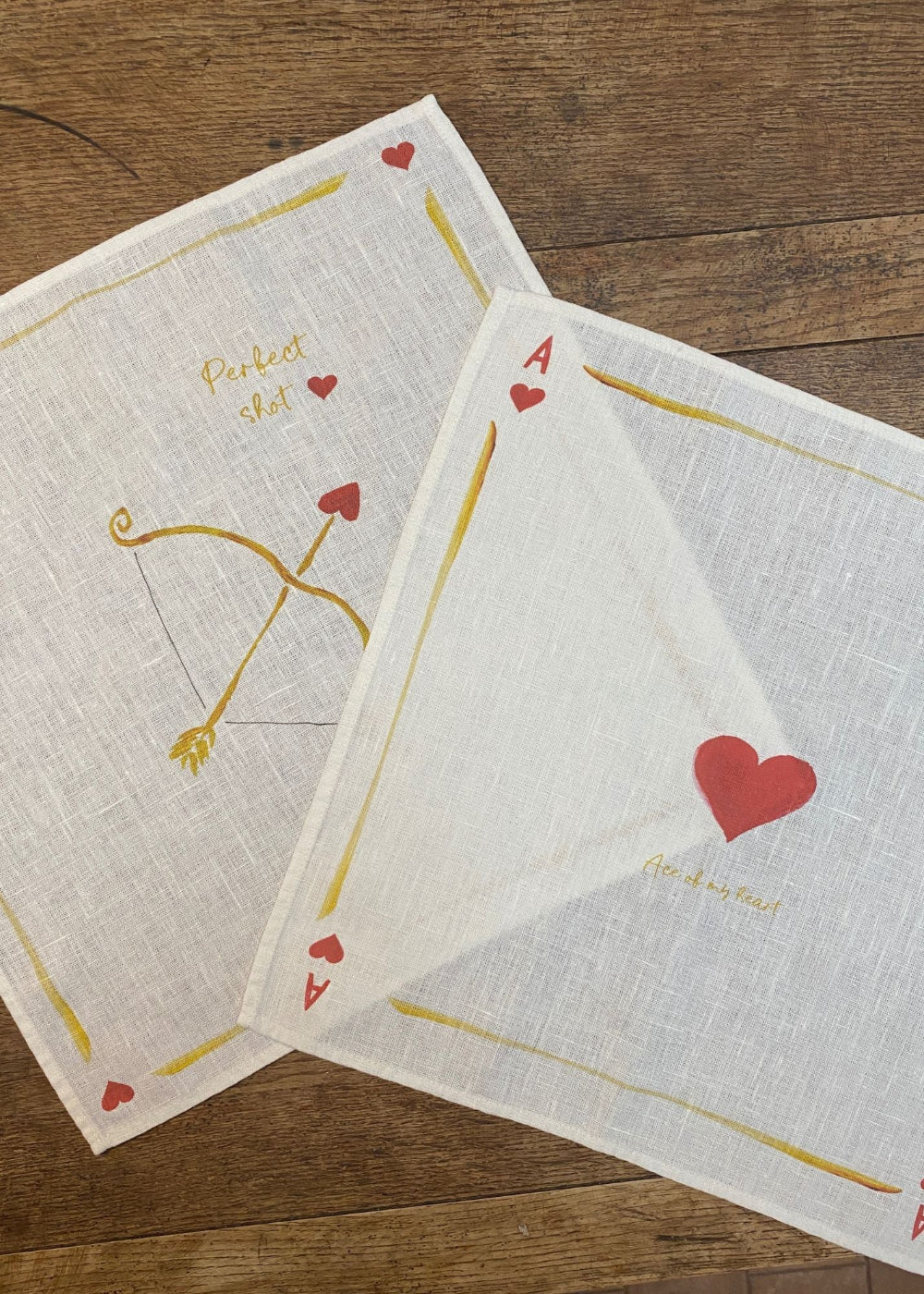 Two playing card-themed napkins on a wooden surface