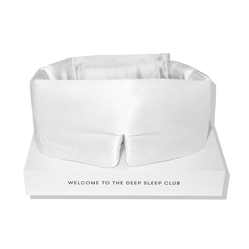 White sleep mask on a white background on top of white box packaging with text 'Welcome to the deep sleep club'