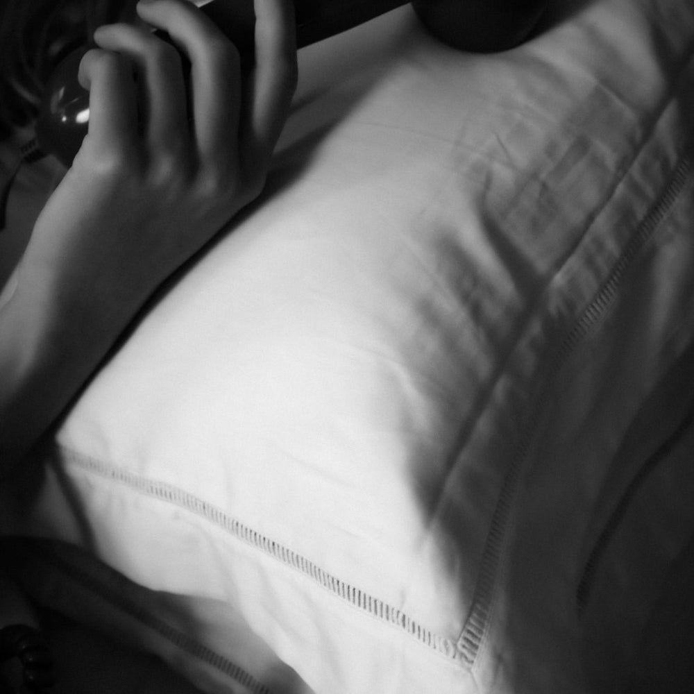 Close-up of a person's hand holding a telephone on the Amalfi White Pillowcase