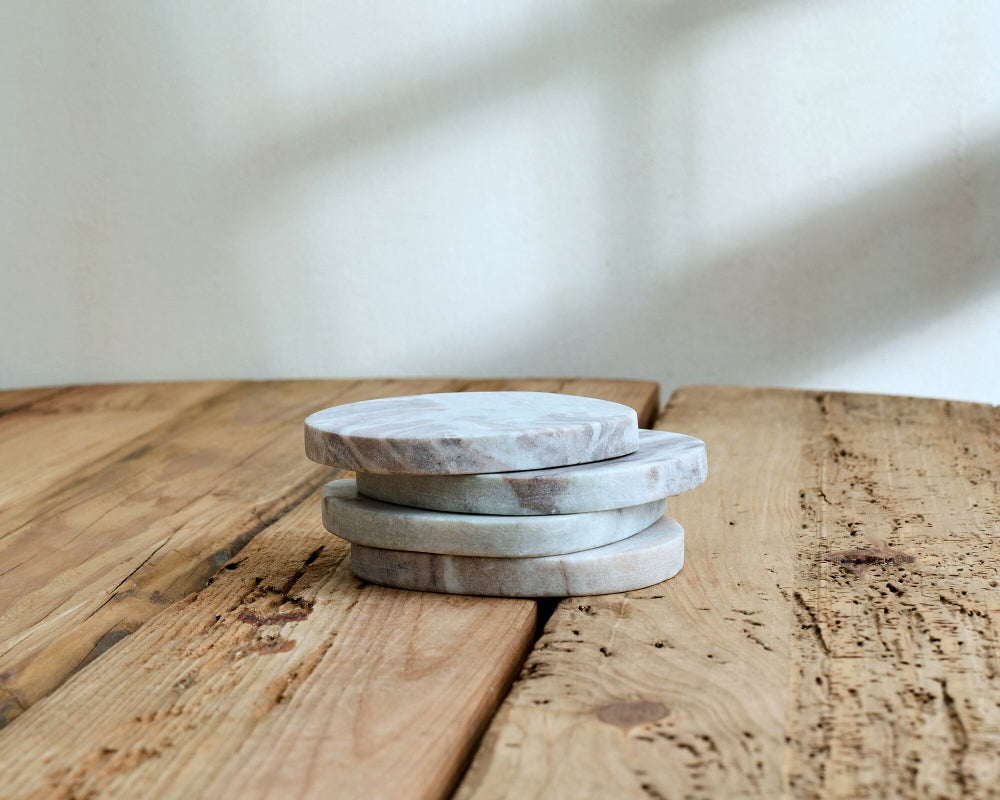 Stack of marble coasters on a wooden surface with a neutral background