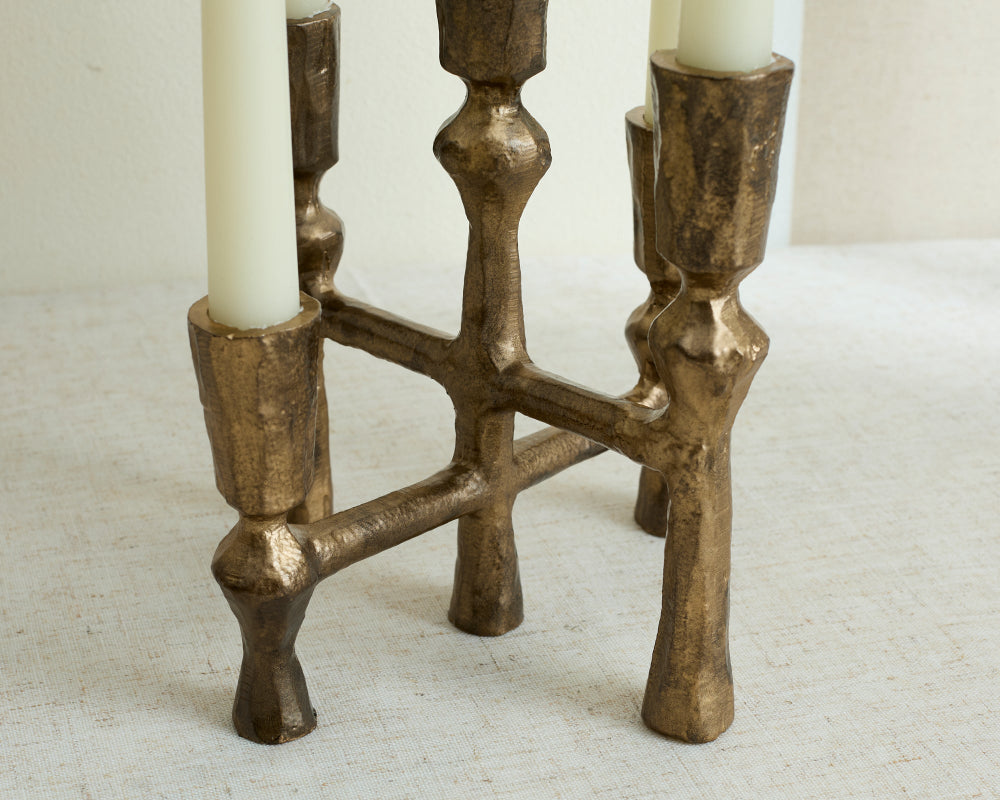 Bronze candle holder with two white candles on a textured surface