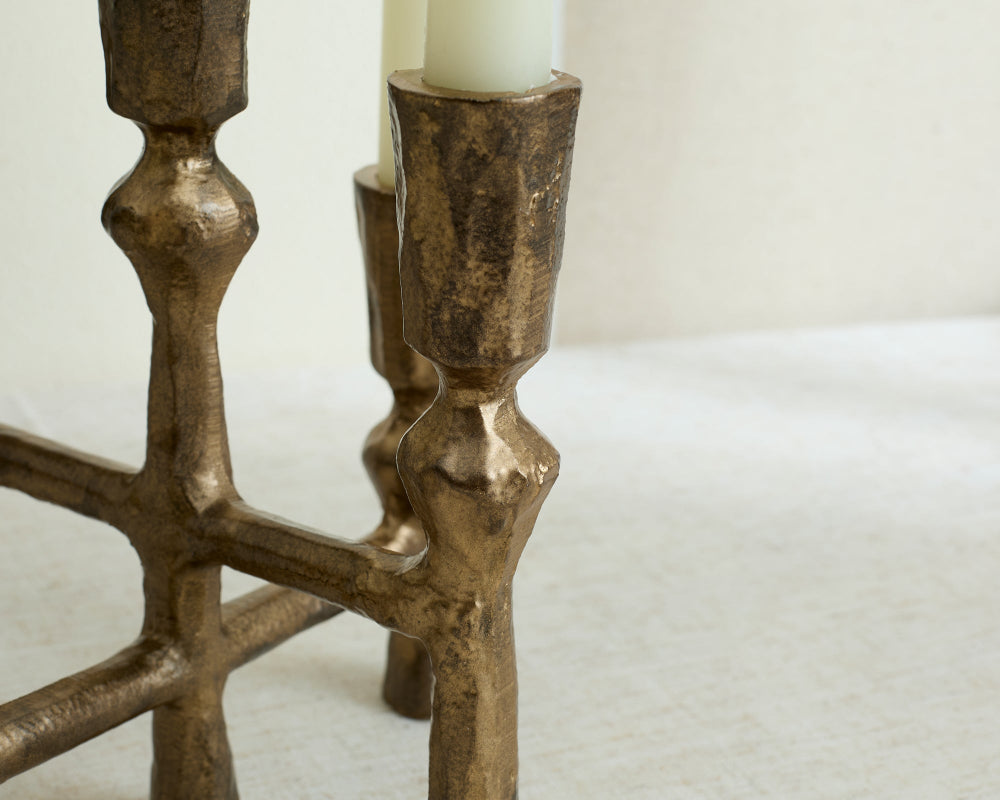 Bronze candle holder with a white candle on a textured surface