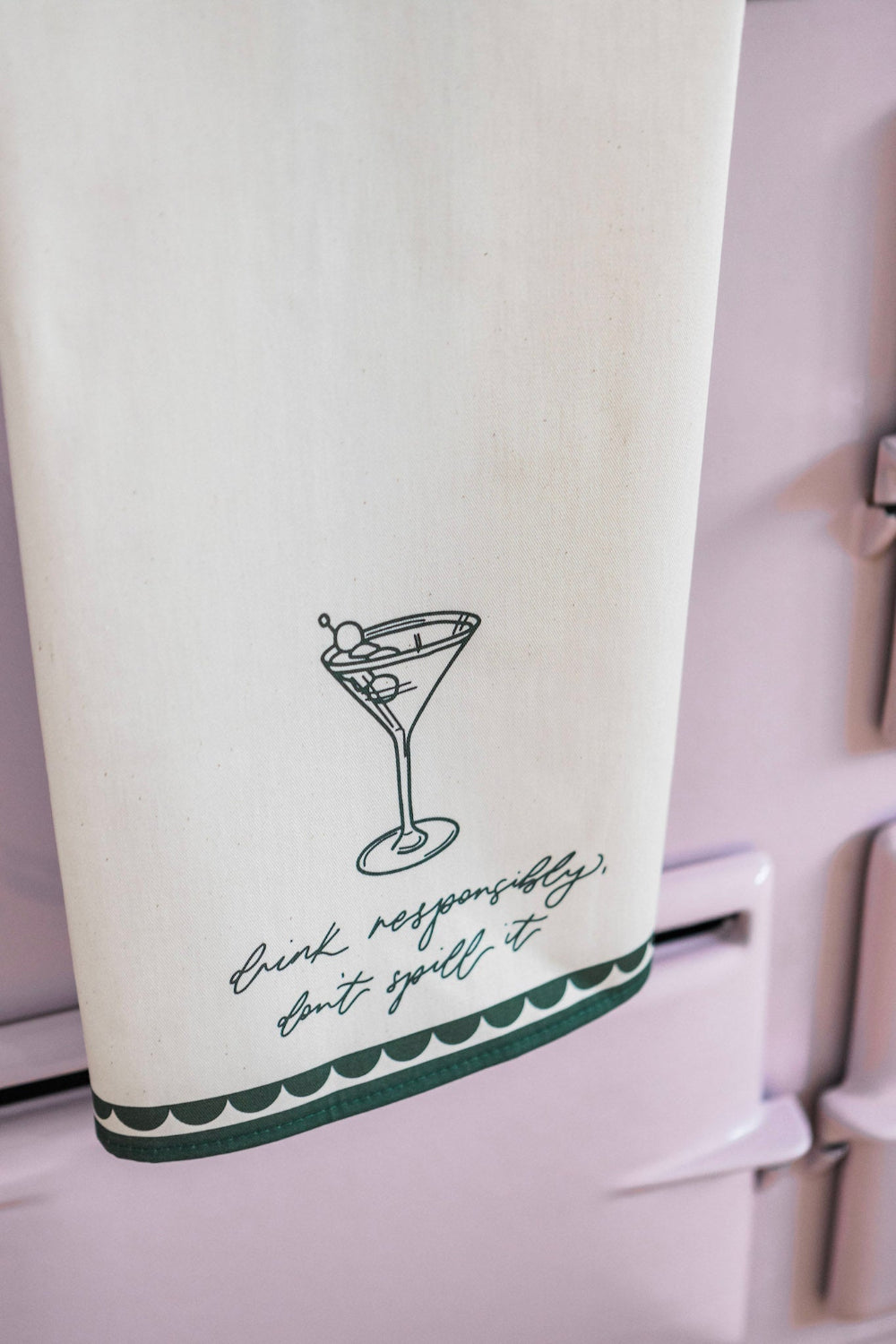 Tea towel with martini glass design and text on a white surface